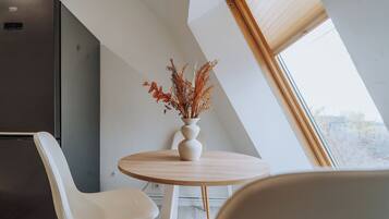 A modern kitchen with a built-in refrigerator, a round wooden table, and white chairs.