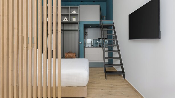 Una camera da letto compatta con un letto, un armadio, una scrivania e una TV.