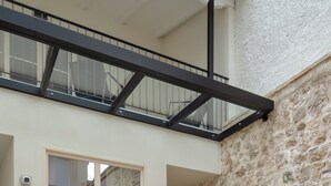Un edificio moderno con facciata in pietra, un'ampia finestra e un balcone con ringhiera metallica.