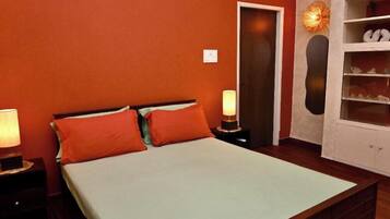 A bedroom with a bed, two nightstands, a wardrobe, and a door.