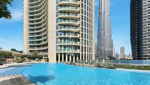Una piscina de borde curvo, rodeada de modernos edificios altos.
