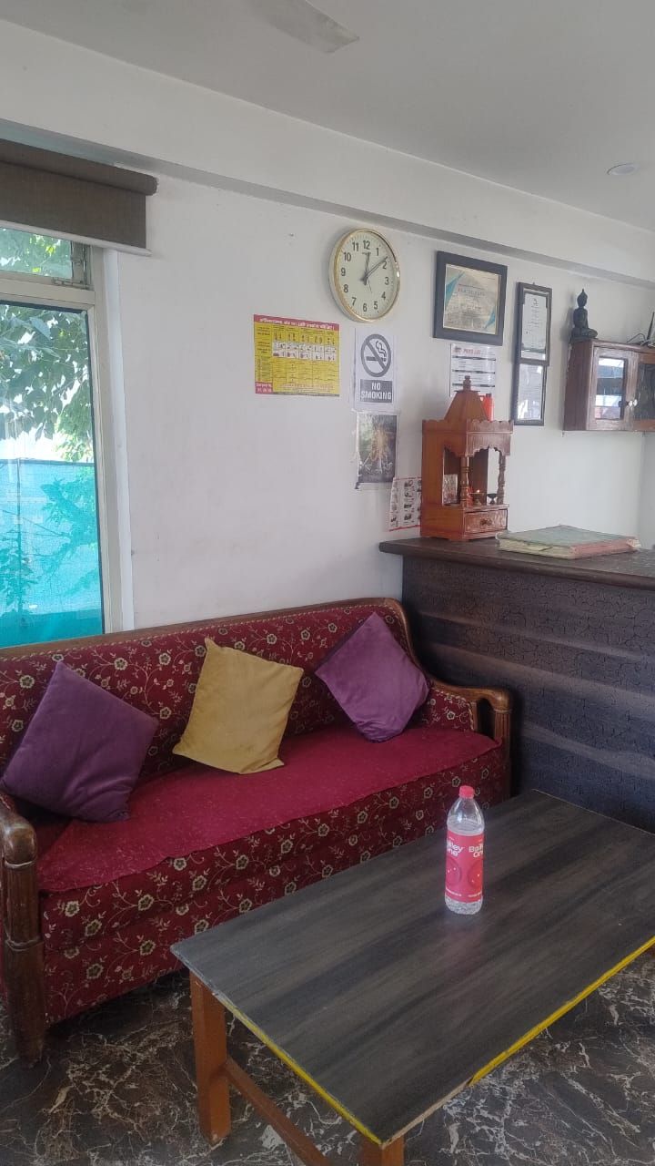 Un área de recepción con un sofá, una mesa con una botella, un reloj y certificados enmarcados en la pared.