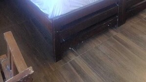 A neatly made bed with white linens and two pillows, a wooden headboard, and a small stack of white towels on the side. - Hotel Aviral Ganga (Rishikesh)