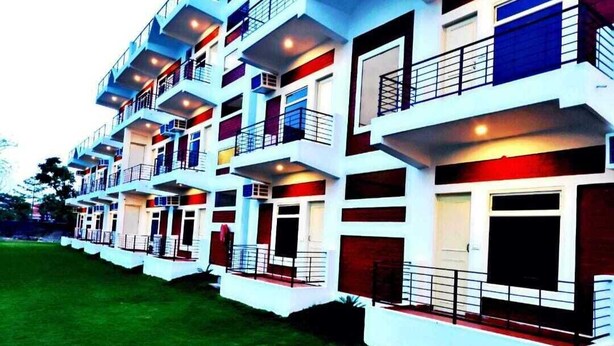 A multi-story hotel with balconies, a flat roof, and a well-maintained lawn. - Hotel Aviral Ganga (Rishikesh)