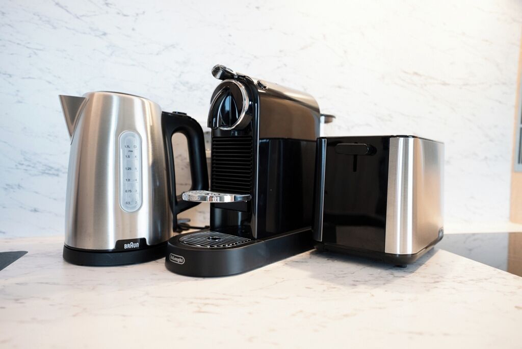A coffee maker with a kettle and a container on a marble countertop.