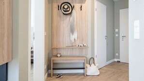 Un couloir avec un banc en bois, un porte-manteau et une porte.