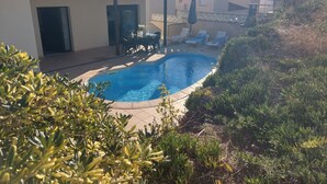 A swimming pool with lounge chairs and a covered patio area. - Casa Quatre Brises (L'Escala)