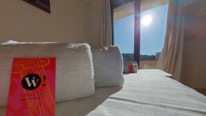 A hotel room with a bed, a window with curtains, and a sign on the bed. - Casa Quatre Brises (L'Escala)