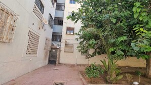 Uma passagem estreita com portão, ladeada por edifícios com janelas e sacadas estampadas.