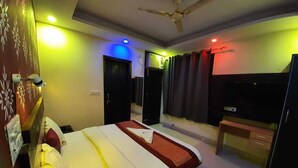 Une chambre d’hôtel équipée d’un lit, d’un bureau, d’une télévision et d’un ventilateur de plafond.