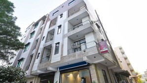 Un hôtel à plusieurs étages, doté de balcons, avec une entrée bien visible et une enseigne indiquant qu’il s’agit d’un hôtel.