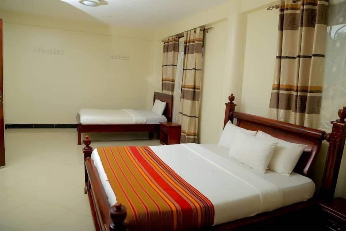 Una habitación de hotel con dos camas individuales, cabeceros de madera y un corredor de cama a rayas.