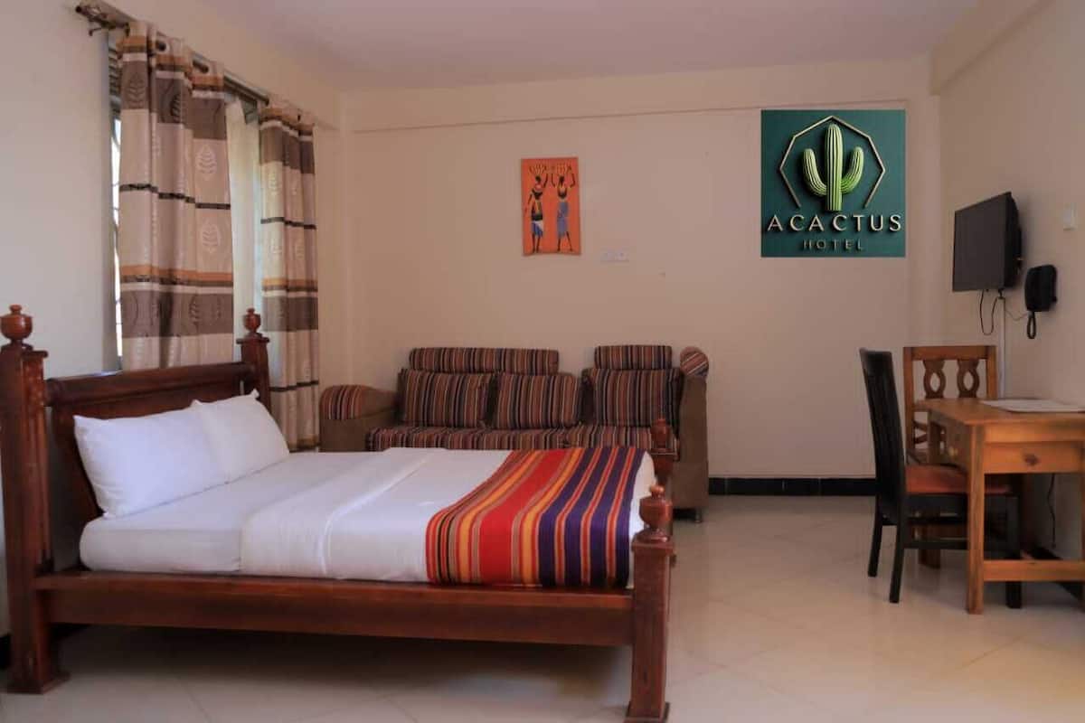 Una habitación de hotel con una cama de madera, un sillón a rayas y un escritorio con una silla.