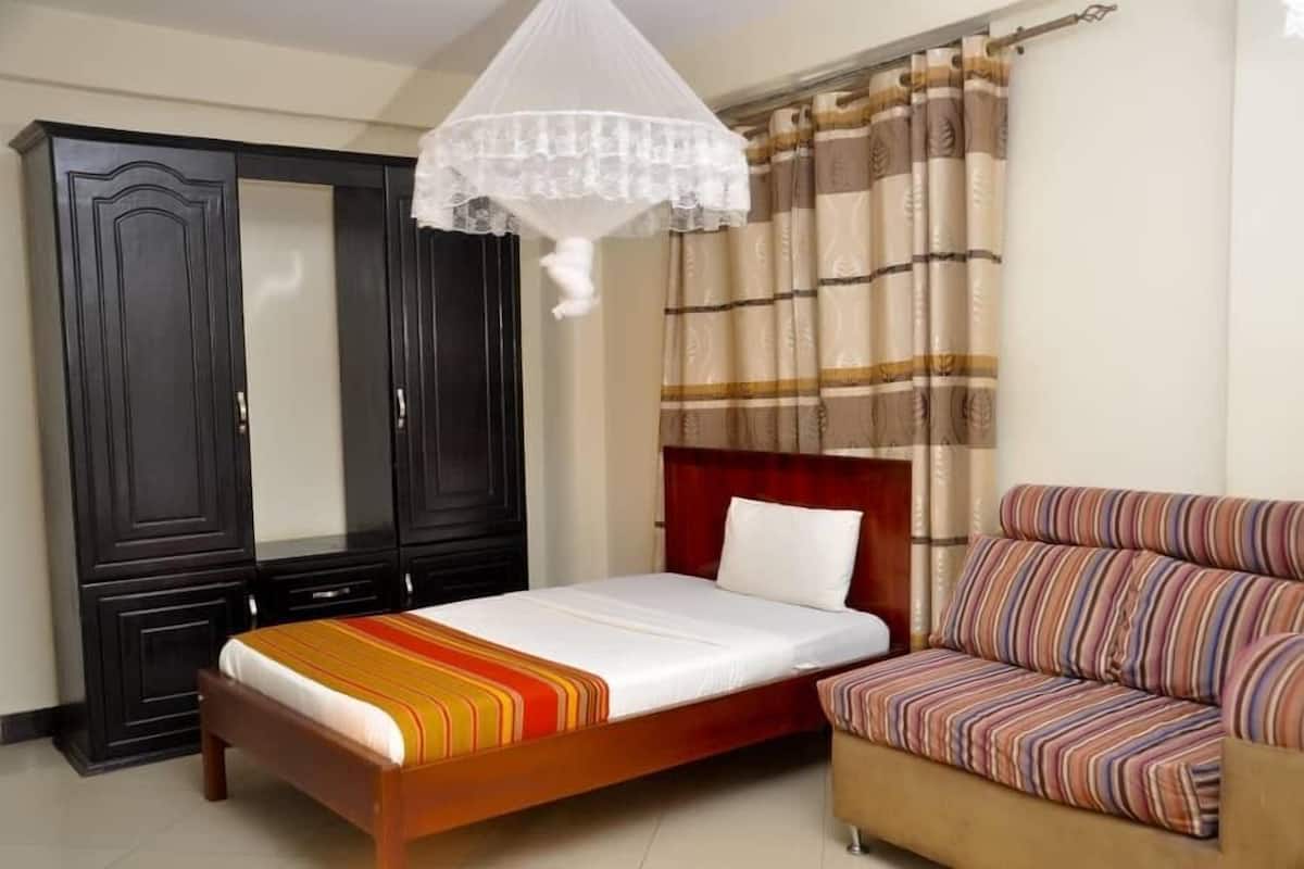 Un dormitorio con una cama, un sofá, un armario y una mosquitera.