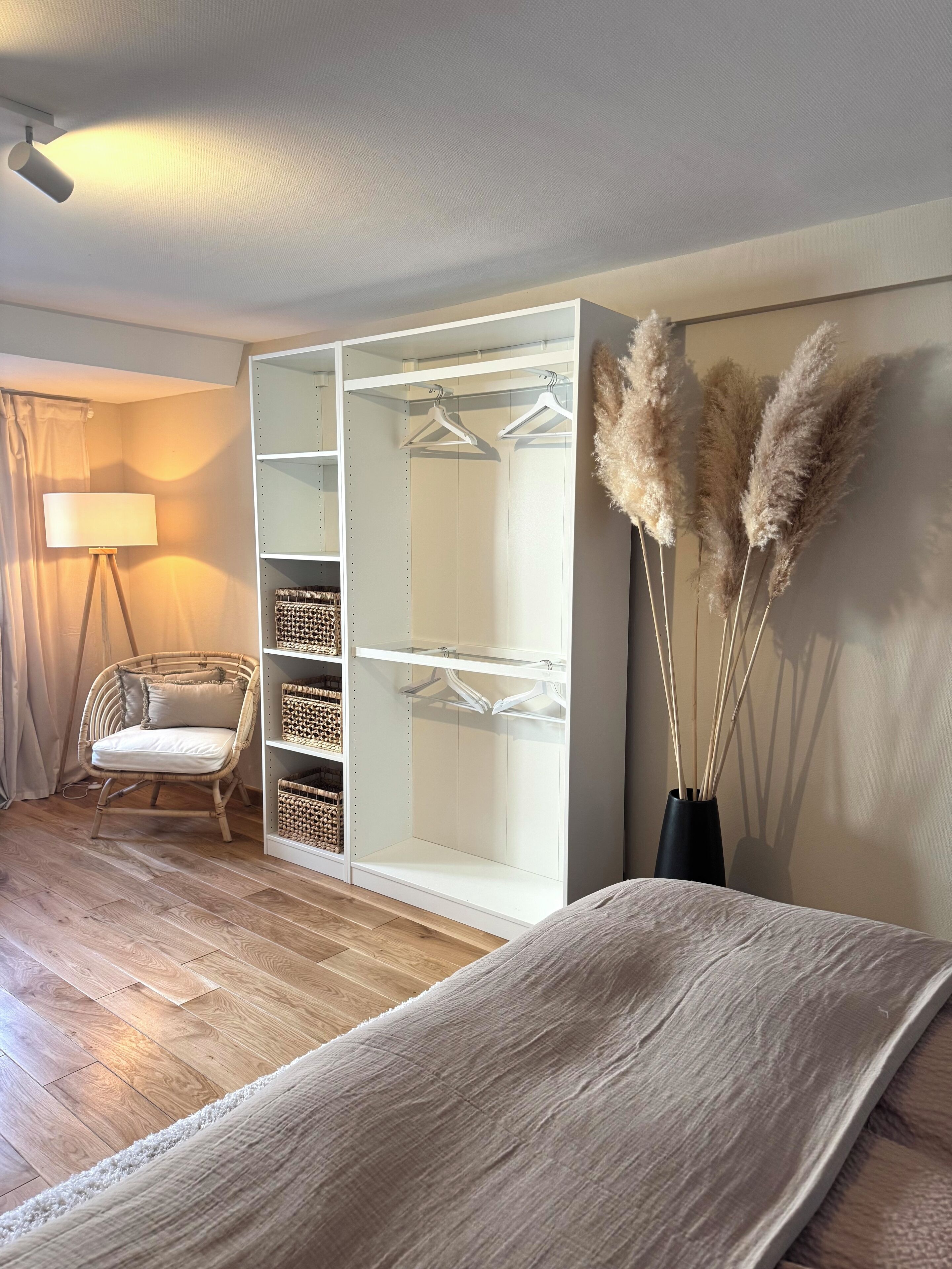 Ein Schlafzimmer mit Bett, Kleiderschrank, Sessel und Lampe.