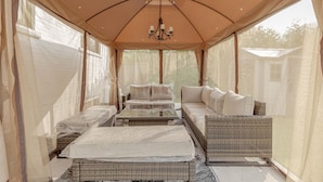 A tented room with a bed, a sofa, and a table.