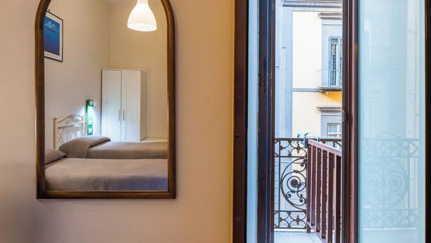 A bedroom with a bed, a wardrobe, and a mirror reflecting the room. - Relax in Centro (Naples)