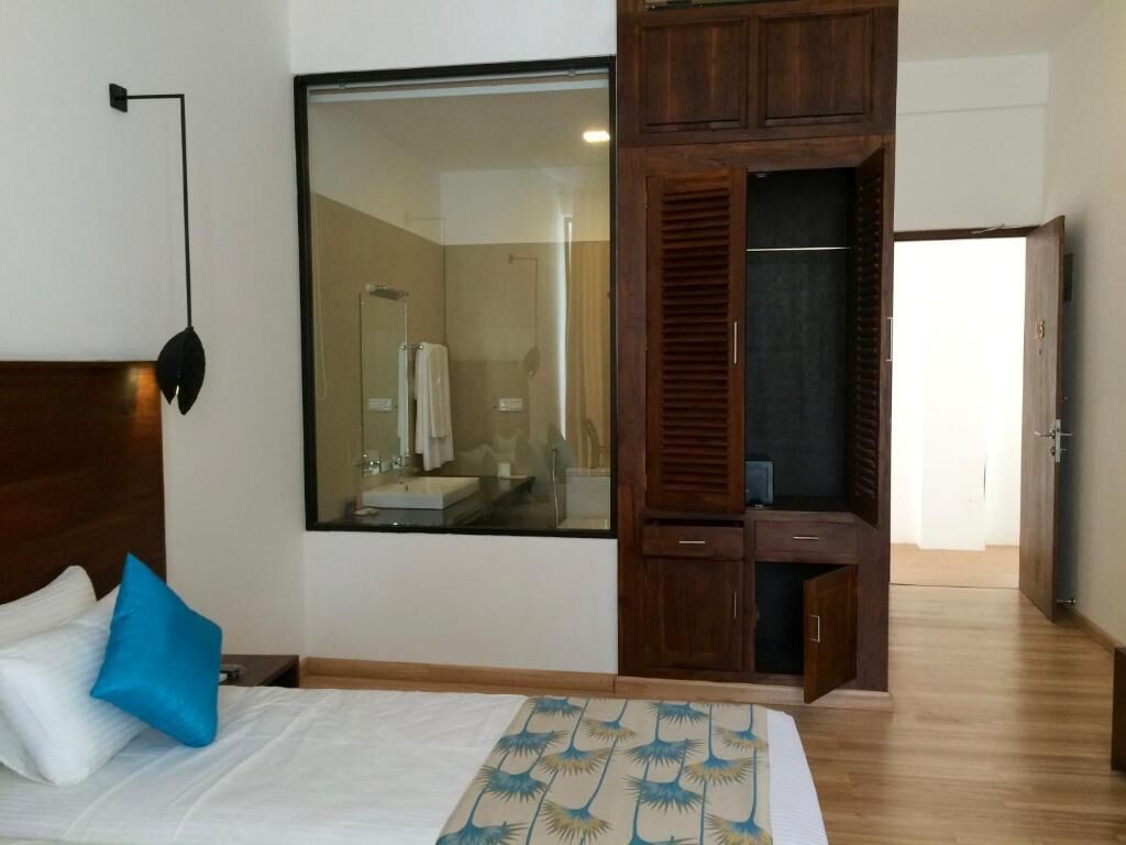 Un dormitorio con una cama, un ventanal grande, un armario y un espejo.