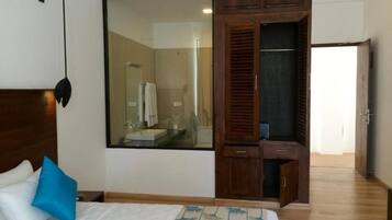 Un dormitorio con una cama, un ventanal grande, un armario y un espejo.