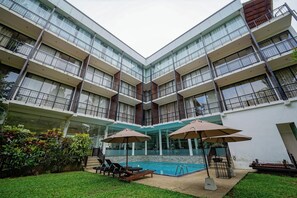 A multi-story hotel with a swimming pool, outdoor seating, and a well-maintained garden. - Rain Tree by Oak Ray (Tissamaharama)