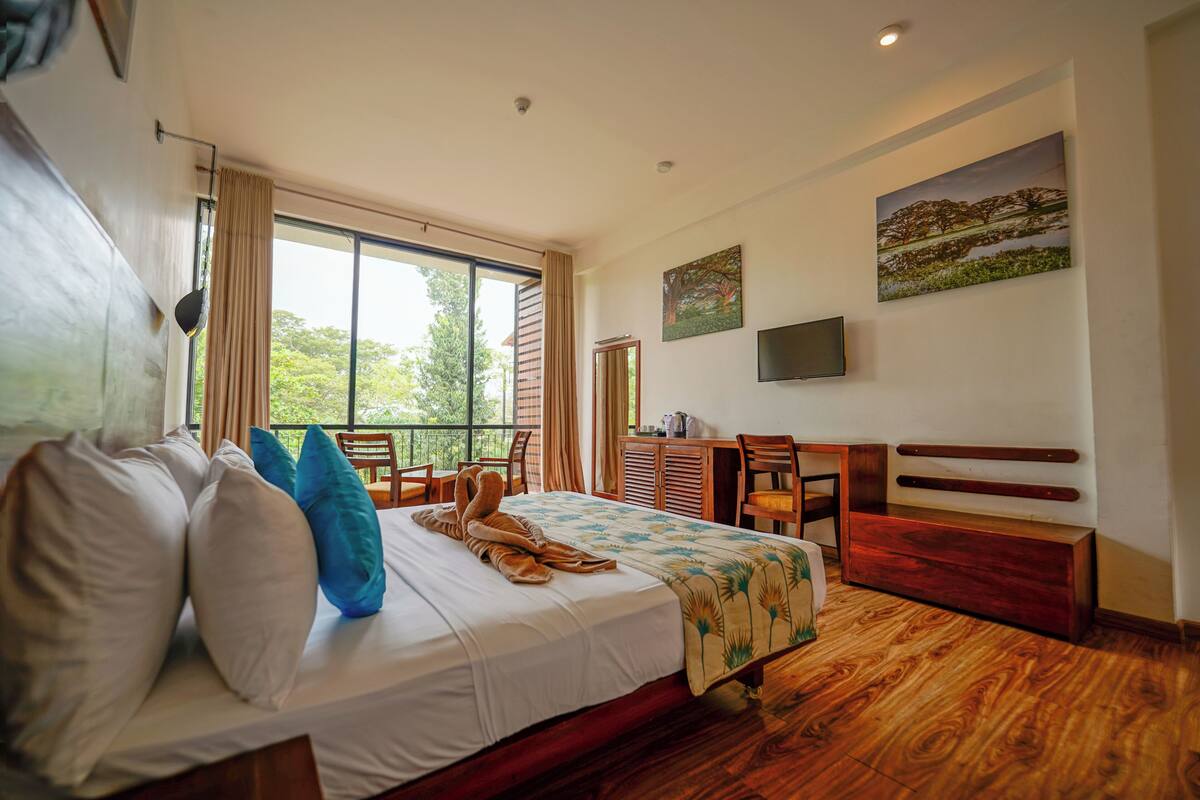 A hotel room with a bed, a desk, a chair, a TV, and a window with curtains.