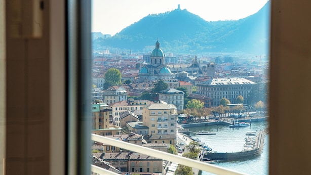 A view of a cityscape with a prominent church and a river. - Infinito (Como)