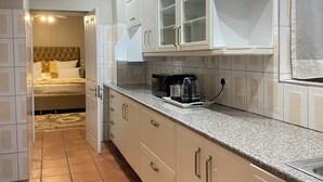 Una cocina moderna con armarios blancos, encimera de granito y cafetera.