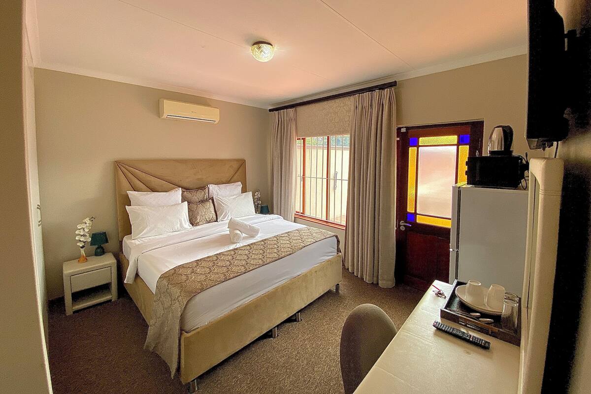 A hotel room with a bed, bedside table, and a desk with a chair.
