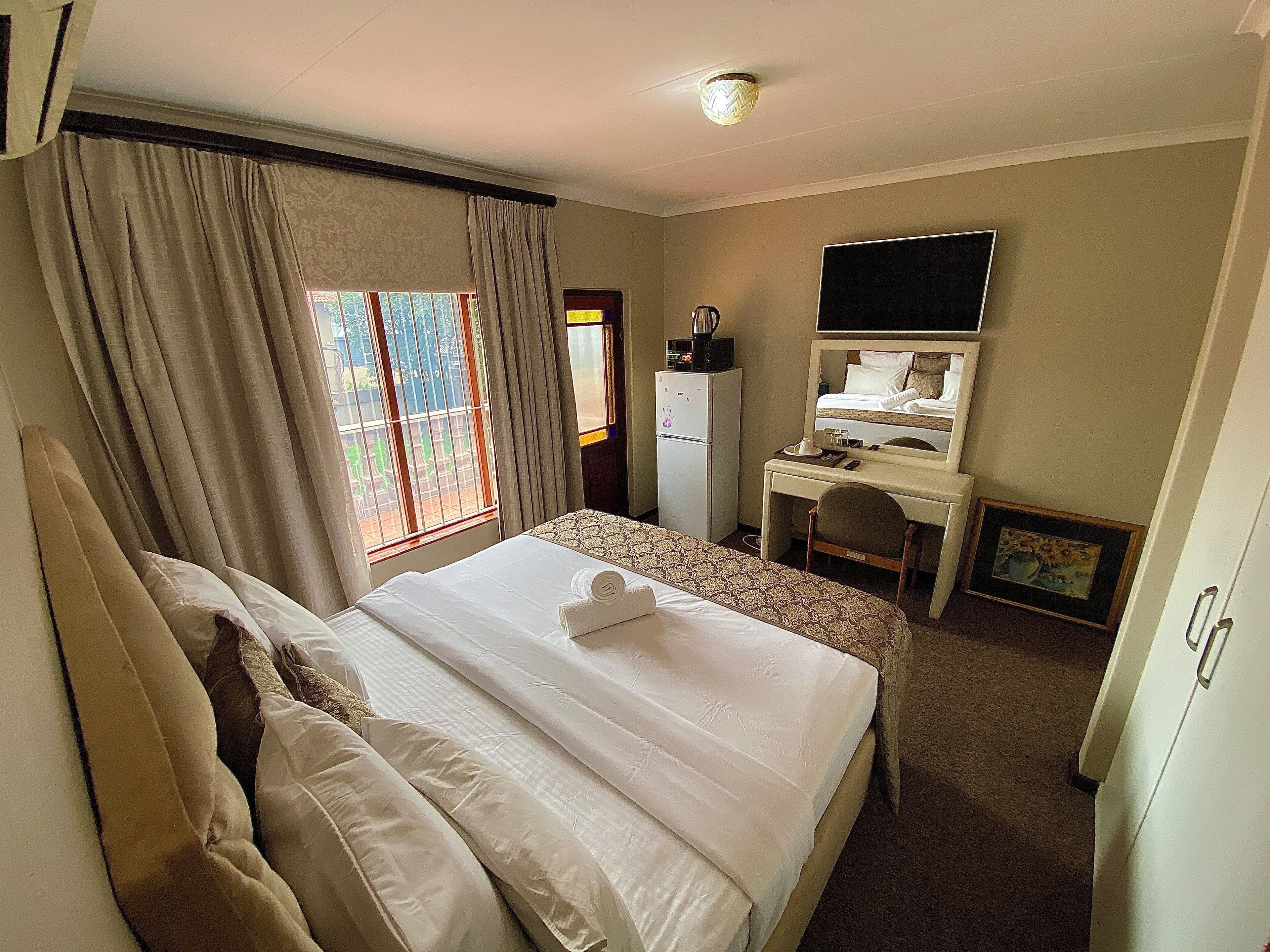 Une chambre d’hôtel équipée d’un lit, d’un bureau, d’une chaise, d’une télévision et d’un réfrigérateur.