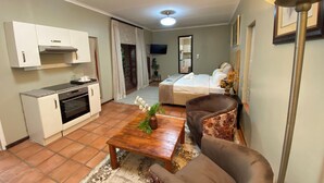 Un espacio habitable compacto con kitchenette, un sofá, una mesa de centro y una cama.