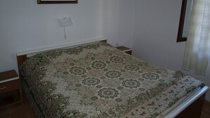 A bedroom with a bed, a nightstand, a lamp, and a painting on the wall. - Ercilia house / Ercilia A2 (Veli Lošinj)