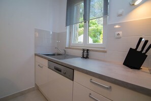 Eine moderne Küche mit eingebautem Geschirrspüler, einem Fenster mit Blick und einem Messerblock auf der Arbeitsplatte.