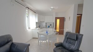 Een moderne woonkamer met een eethoek, een keuken en een deur naar een andere kamer.