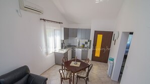 Ett kompakt bostadsutrymme med en matplats, ett litet kök och en svart lädersoffa.