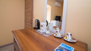 A wooden dresser with a coffee maker, a kettle, and a plate with a cup. A mirror reflects a room with a TV and an air conditioner. - Luisa Rooms / Luisa room B2 (Veli Lošinj)