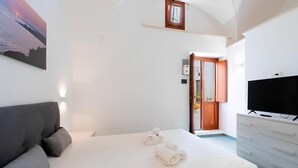 A bedroom with a bed, a TV, and a painting on the wall. - Dimora Giulietta, modern accommodation with vaulted ceilings, in a Salento courtyard (Miggiano)