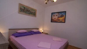 A bedroom with a bed, pillows, a nightstand, and two wall-mounted paintings.