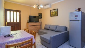 A compact living space with a dining table, sofa, and a refrigerator.