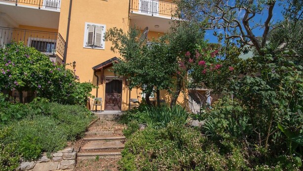 A yellow building with a stone staircase leading to a wooden door.