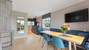 Una cucina moderna con zona pranzo, un'ampia televisione e una finestra vista.