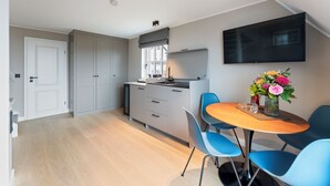 Eine moderne Küche mit grauen Schränken, einem eingebauten Backofen und einem Essbereich mit einem runden Holztisch und blauen Stühlen.