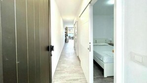 A narrow hallway with a wooden floor leading to a room with a bed and a white wall. - Apartment with pool south of Tenerife (CN)
