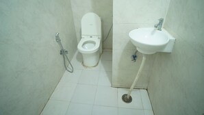 Een kleine, schone badkamer met toilet, wastafel en douche.