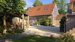 A house with a gravel driveway, a covered patio, and a stone wall. - La linoterie Sauna privatif (Colembert)
