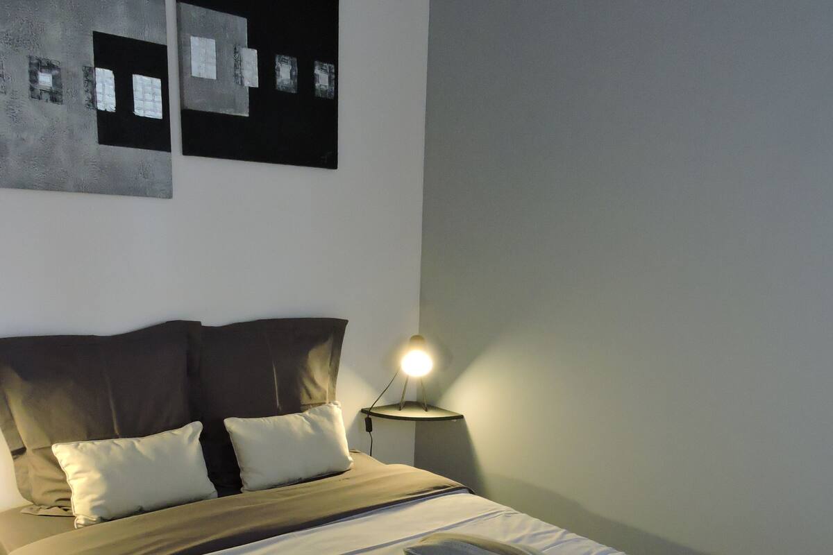 Una cama bien hecha con almohadas y una lámpara de noche.