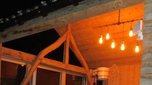 A wooden cabin with a hot tub, wooden beams, and hanging lights. - La linoterie Sauna privatif (Colembert)