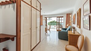 Ein Zimmer mit großem Schrank, einer Couch, einem Korbstuhl und einem Esstisch.