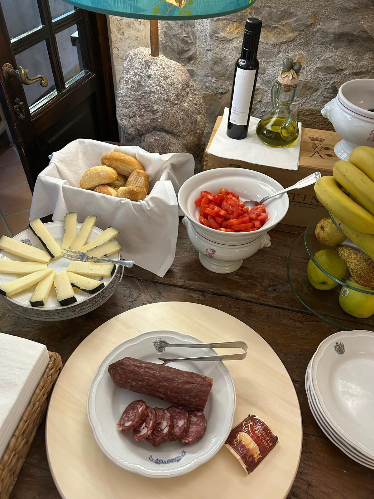A table set with various food items including cheese, cured meats, bread, and fruits.