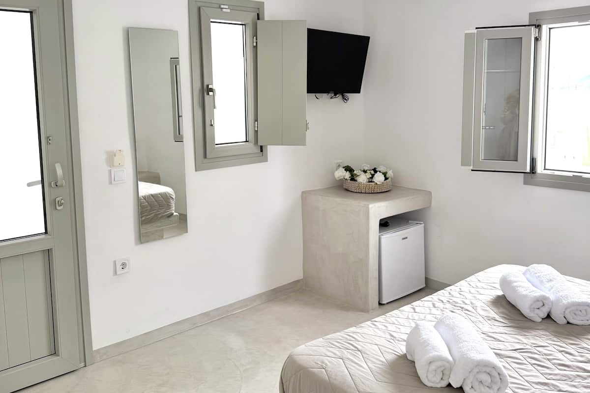 Een hotelkamer met een bed, een klein bureau, een televisie en een raam.