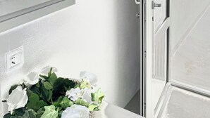 A room with a window, a door, and a wall-mounted air conditioning unit. - Fira Heart Studios (Santorini)